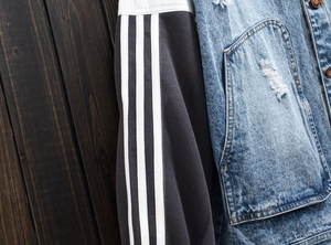 Close-up detail of denim jacket showing distressed fabric and contrast knit sleeves