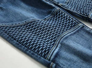 Détail du jean biker bleu avec empiècements côtelés et texture denim délavée