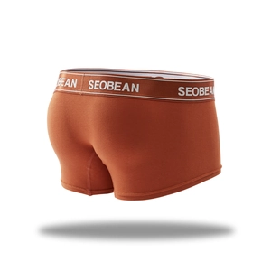 Detail view of men's knitted orange boxer briefs with elastic logo waistband and soft fabric