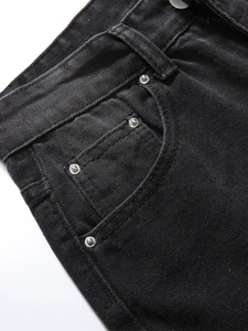 Detailansicht der verstärkten Nähte und Metallnieten an den schwarzen Jeans-Taschen