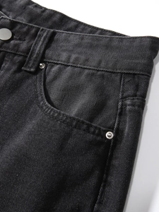 Detailansicht aus gewaschenem schwarzem Denim mit Metallknopf und Nietentaschen