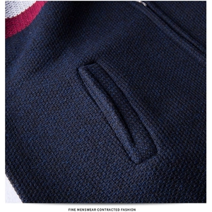 Detail of navy knit sweater with red-white stripes, metal zipper, and side pocket