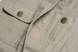 Dettaglio ravvicinato del gilet kaki con bottoni in metallo e tasche con patta cucite
