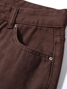 Detailaufnahme einer braunen Jeans mit Stofftextur, Vordertasche und Metallnieten aus der Nähe