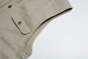 Dettaglio del gilet utility kaki con robusto tessuto in tela e bottone in ottone