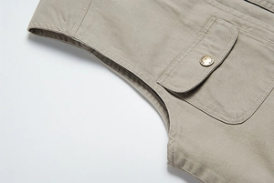 Dettaglio ravvicinato del gilet in twill di cotone kaki con taschino e bottone metallico