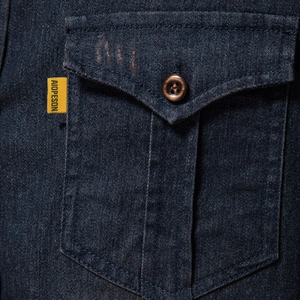 Détail de la poche de chemise en jean bleu foncé avec bouton vintage et étiquette