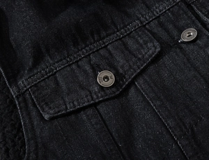 Detailed close-up of black denim vest featuring metallic buttons and reinforced pocket stitching