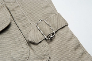 Macro della fibbia in metallo argento su dettaglio di gilet in twill color kaki