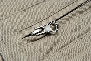 Dettaglio macro della cerniera in metallo e del tessuto twill sul gilet color kaki