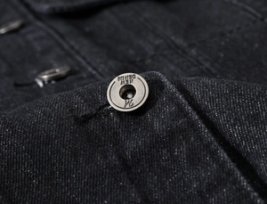 Close-up of vintage metal button on black fleece-lined denim vest for men