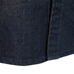 Gros plan sur la texture du denim bleu foncé et les doubles coutures d'une chemise homme