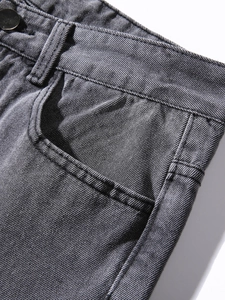 Dettaglio dei jeans grigi che mostra il bottone metallico e le cuciture sulla vita