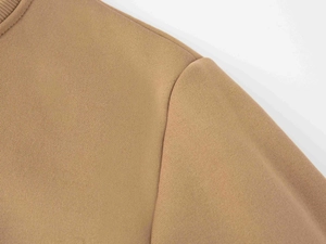 Dettaglio della cucitura della spalla su una felpa a maniche lunghe color cammello