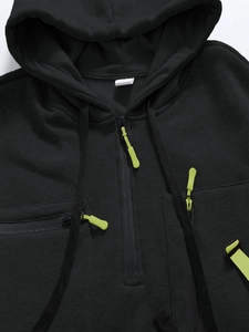 Close-up of black hoodie with neon green zippers and 100% polyester fabric detail