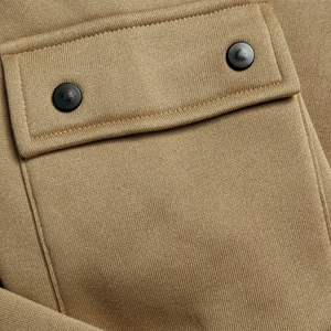 Detail of khaki hoodie pocket with double black buttons and high-density knit fabric texture