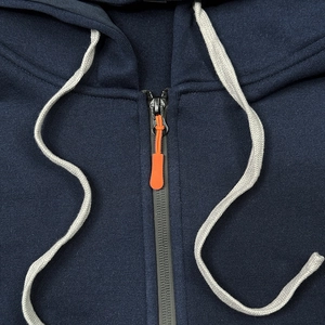 Detail eines dunkelblauen Hoodies mit orangefarbenem Reißverschluss und weißen Kordeln