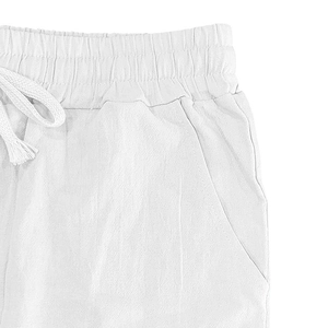 Detail of white cotton linen trousers showing elastic waistband with a woven drawstring