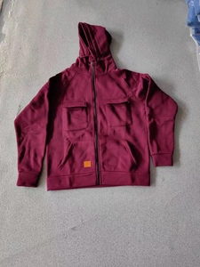 Detail of burgundy hoodie showing front pockets and orange square patch on hem