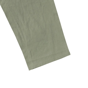 Detail of sage green cotton linen pants showing fiber texture and double stitching