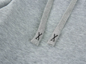 Gros plan des cordons de sweat gris avec broderie noire en forme de X aux extrémités