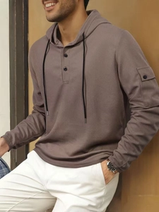 Details von Waffelstrick und Ärmeltasche an khakifarbenem Kapuzen-Henley-Shirt