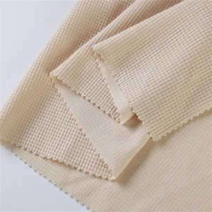 Detaillierte Makroansicht des beigen Waffelstrickstoffs mit dem hochwertigen Wabenmuster