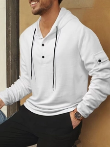 Makroaufnahme von weißem Waffelstrickstoff am Herren-Hoodie mit schwarzen Kontrastknöpfen