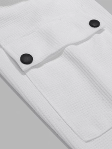 Detailansicht von weißem Waffelstrickstoff mit Taschendeckel und schwarzen Knöpfen