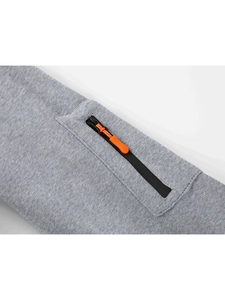 Detail of grey sweatshirt showing a black zipper pocket with bright orange woven pull cord