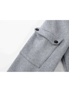 Detailed macro view of light gray knit hoodie pocket with two matte black snap buttons