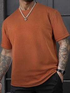 Makroaufnahme eines herren T-Shirts in Ziegelorange mit Waffelstrick-Stoffstruktur