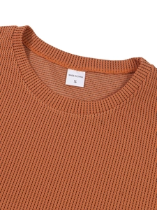 Nahaufnahme des Rundhalsausschnitts eines braunen Waffelstrick-T-Shirts mit feiner Textur