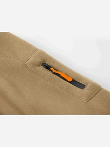 Dettaglio della giacca kaki con cerniera in nylon nero e tirante arancione brillante
