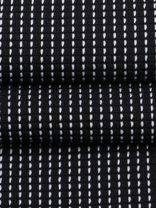 Makroansicht von schwarzem Strickstoff mit weißen gepunkteten vertikalen Streifen