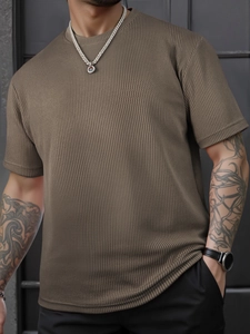 Detailaufnahme der Waffelstrick-Stoffstruktur und des Rundhalsausschnitts des braunen Herren-T-Shirts