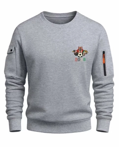Détail de la manche du sweat gris avec poche à fermeture éclair orange et bouton pression