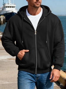 Men's black zip-up hoodie with hood and kangaroo pockets on a seaside dock background