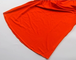 Dettaglio dell'orlo di una t-shirt arancione con scollo a V in tessuto morbido e liscio