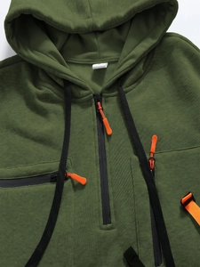 Dettaglio della felpa con cappuccio verde militare con cerniere nere e arancioni