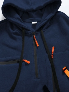 Dettaglio felpa con cappuccio blu con mezza zip, tiralampo arancione e trama tessuto