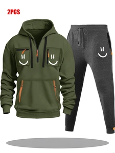 Detail of olive green hoodie with multiple zippers, orange accents and white smiley logo