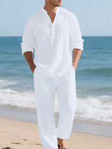 Men's white linen resort set with long sleeve button shirt and relaxed trousers at beach