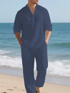 Close-up of navy linen shirt with three-button collar and loose matching trousers on beach