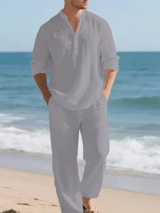 Detail of men's gray linen leisure set featuring a three-button henley collar on a beach