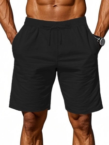 Detail of men's black cotton linen shorts featuring elastic drawstring waistband and pockets