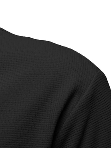 Close-up of black waffle knit fabric showing texture and double collar stitching
