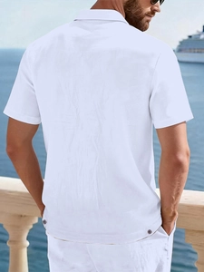 Detail view of the back hem featuring decorative buttons on a white linen beach shirt