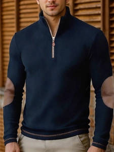Detail view of navy half-zip knit sweater featuring brown leather-trimmed zipper and elbow patches
