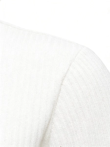 Detailed close-up showing the ribbed knit texture and shoulder seam on the white polo shirt